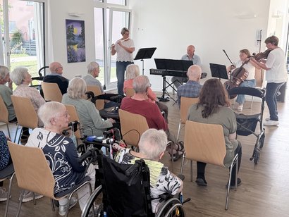Bewohnerinnen und Bewohner genießen ein Kammermusikkonzert mit Querflöte, Violine, Cello und Klavier im Seniorenzentrum Am Feldrain.