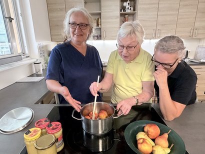 Drei Frauen stehen vor einem Kochtopf voller Äpfel.