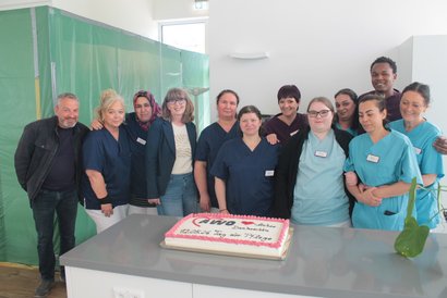 Pflege‑ und Betreuungsteam des AWO‑Seniorenzentrums Am Feldrain steht gemeinsam vor einer Torte anlässlich des Tages der Pflege