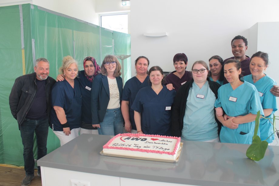 Pflege‑ und Betreuungsteam des AWO‑Seniorenzentrums Am Feldrain steht gemeinsam vor einer Torte anlässlich des Tages der Pflege