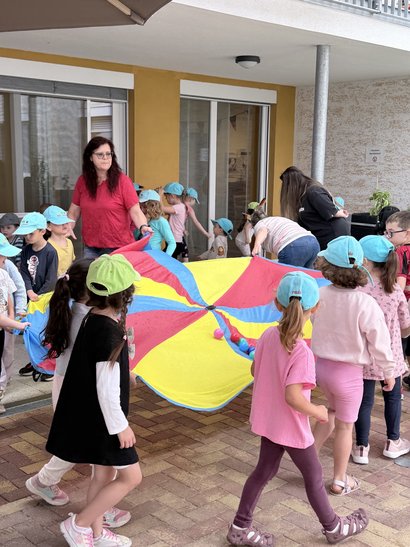 Kinder drehen sich im Kreis mit einem Schwungtuch