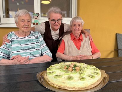 Drei Damen sitzen vor einem selbstgebackenen Kuchen.