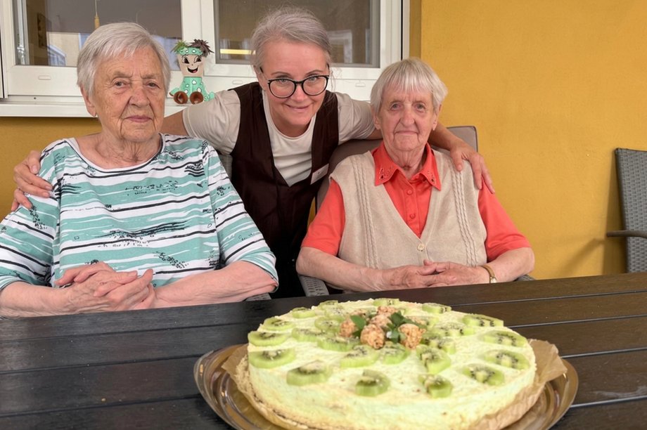Drei Damen sitzen vor einem selbstgebackenen Kuchen.