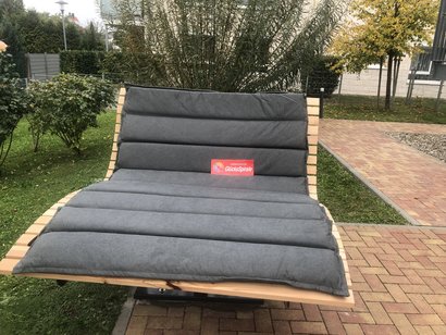Barrierefreie Doppelliege im Gartenbereich eines Seniorenzentrums, gefördert durch die GlücksSpirale, umgeben von Grünflächen und Wegen.